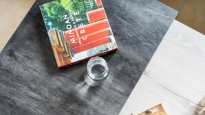 Un libro titulado 'MINOR HISTORIC & NORMAN HELLISTIC & ROMAN' sobre una mesa de madera con una botella de vidrio transparente y una caja de té.