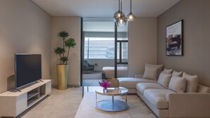 A modern living room with a flat-screen TV, a sofa, a coffee table, and a large window. - Steigenberger Residence Doha (Doha)