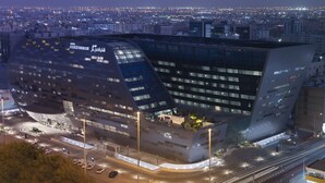 A modern hotel with a distinctive curved facade, multiple floors, and a rooftop area with outdoor seating. - Steigenberger Residence Doha (Doha)