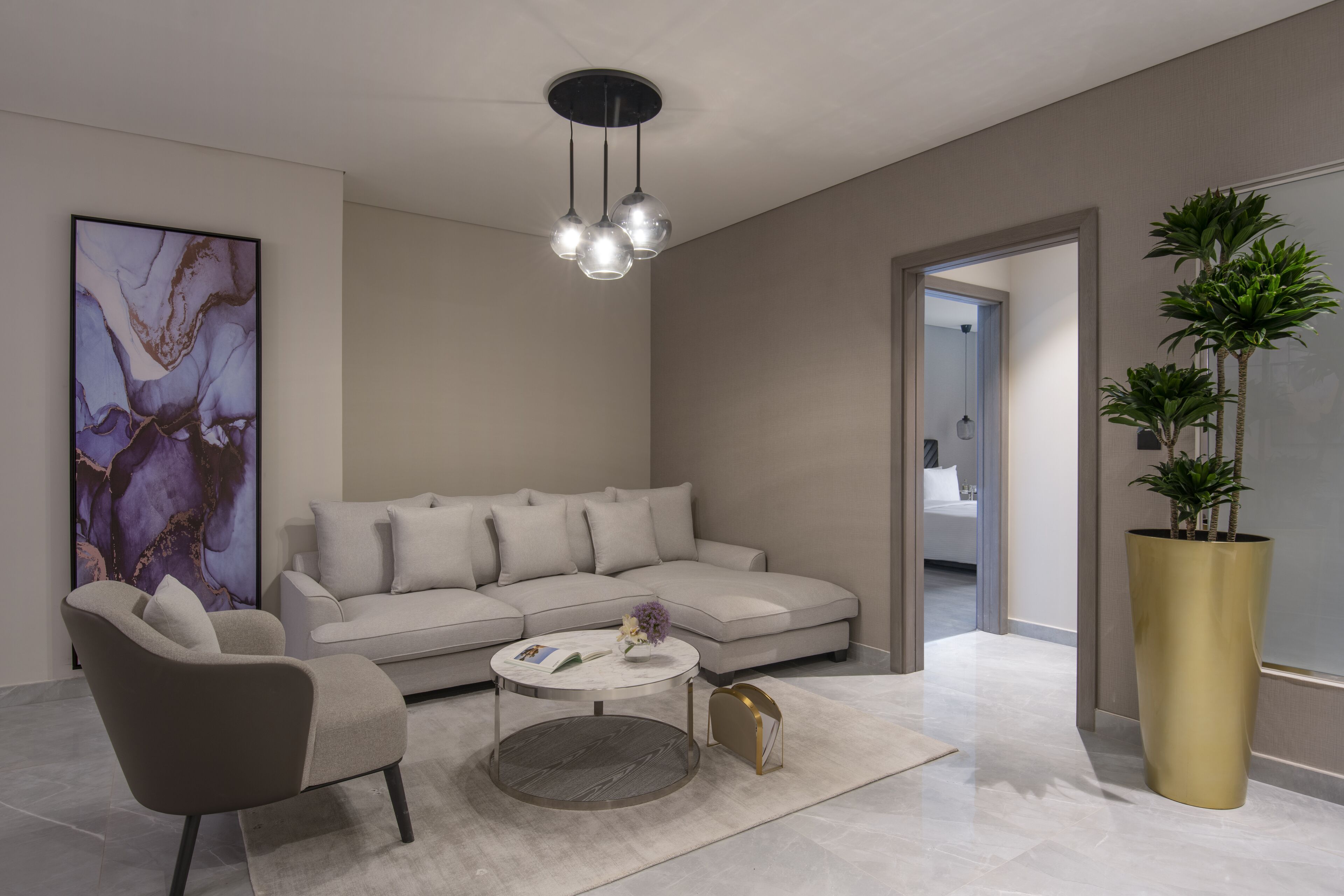 Ein modernes Wohnzimmer mit einem grauen Sofa, einem runden Couchtisch und einem großen abstrakten Gemälde an der Wand.