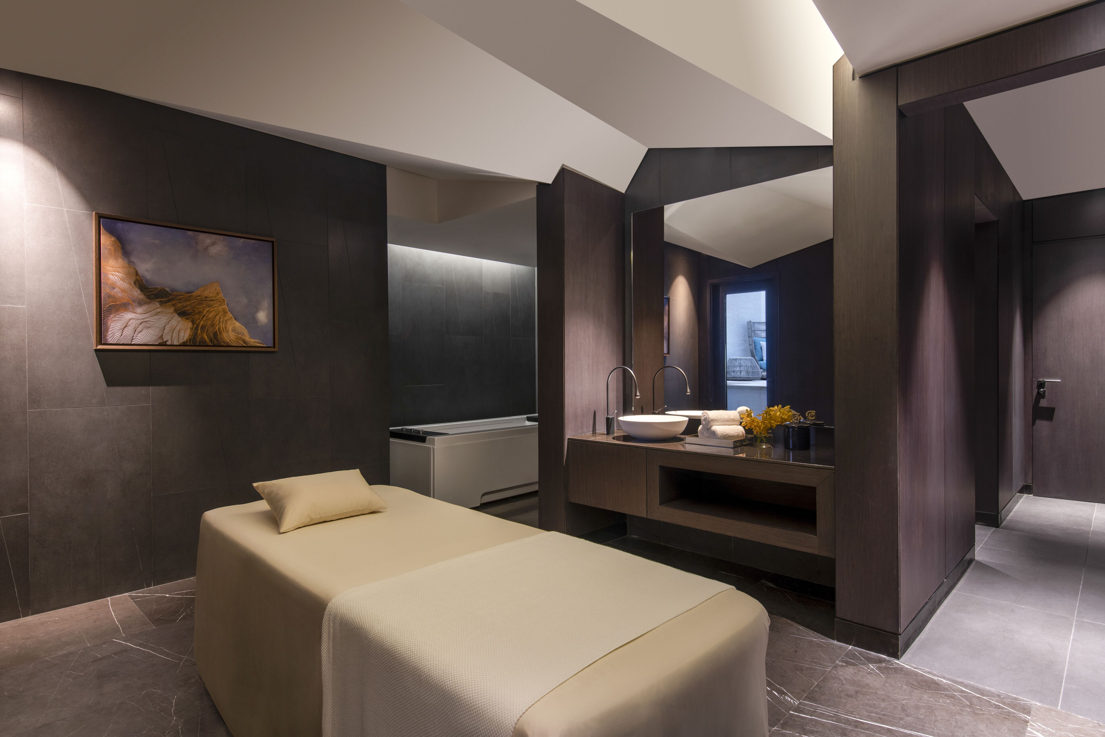Una habitación de hotel moderna con una cama grande, un tocador empotrado con espejo y un cuadro en la pared.