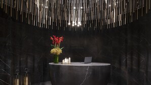 A reception desk with a laptop, candles, and flowers. - Steigenberger Residence Doha (Doha)