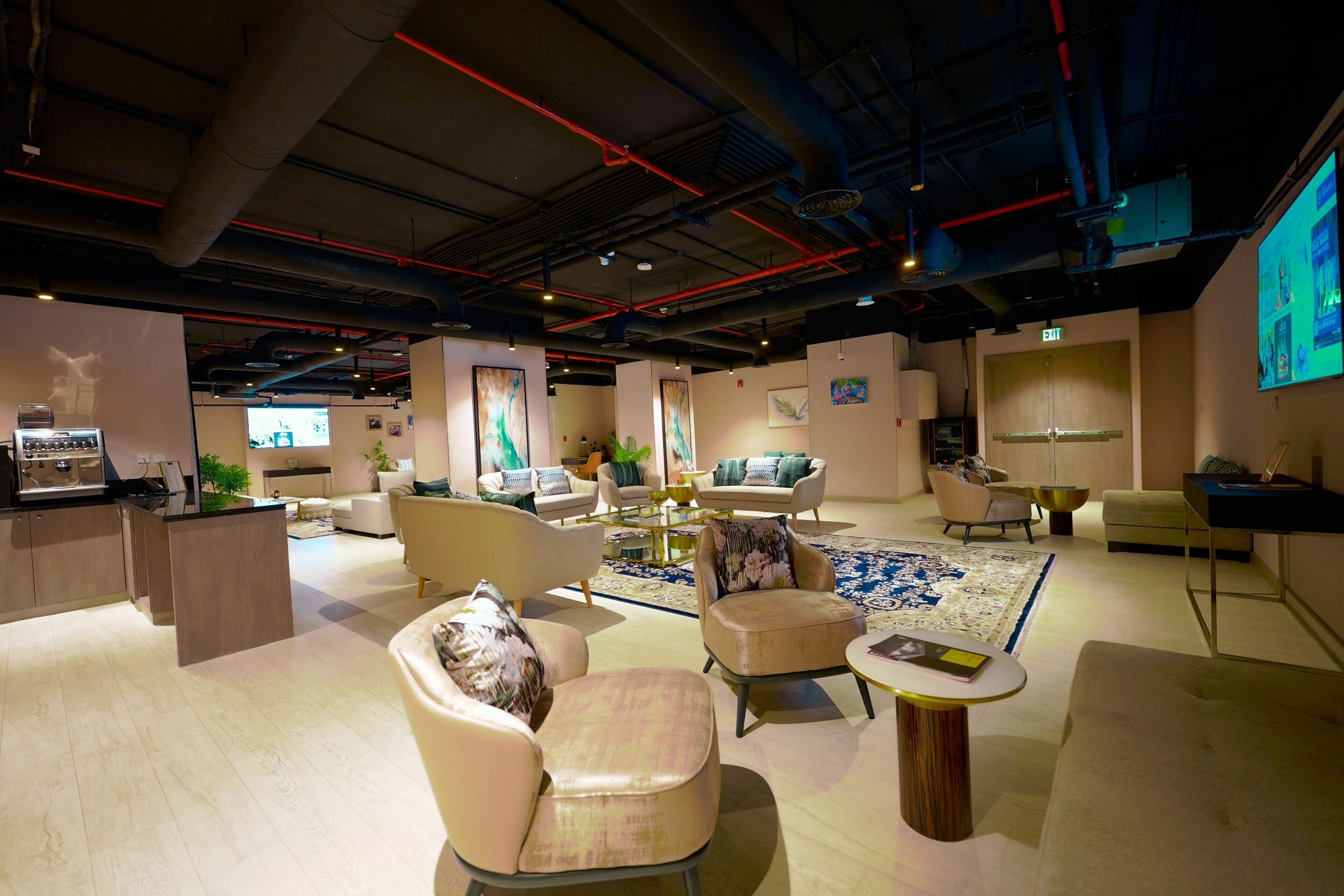 A modern interior with a central seating area, a kitchen, and a projection screen.