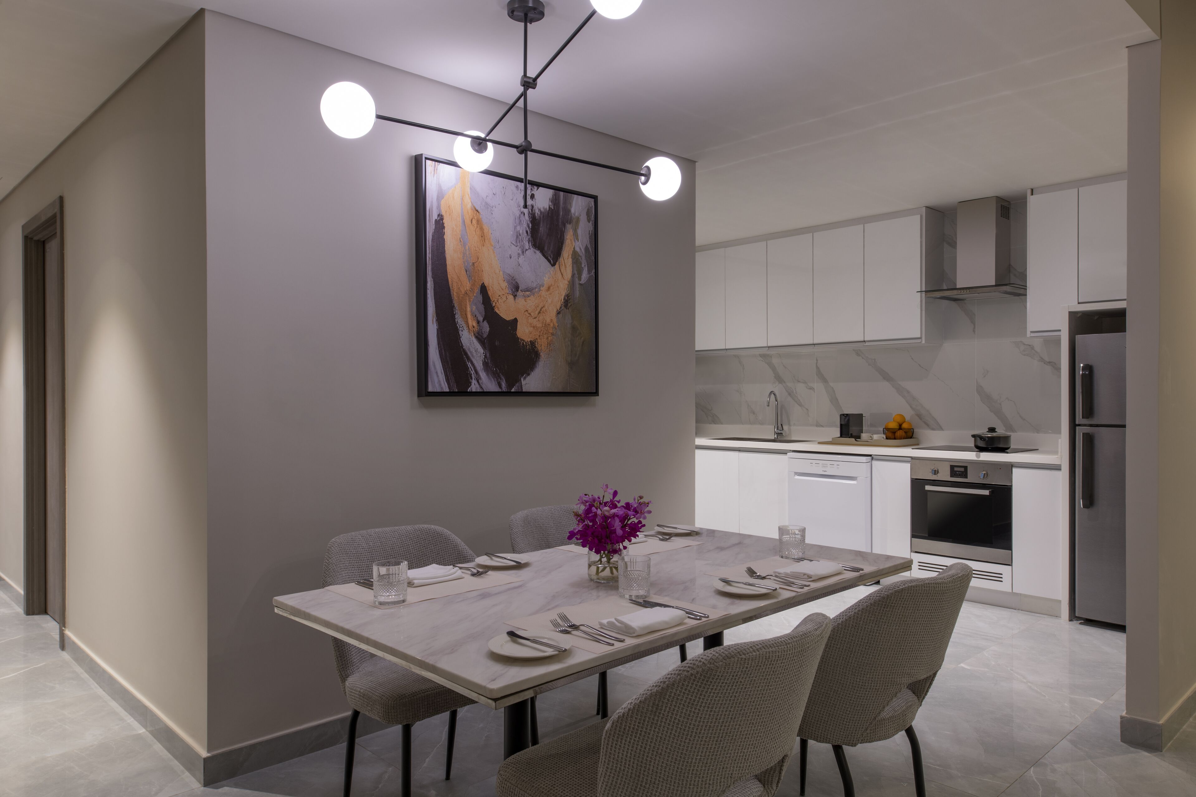 A modern dining area with a marble table, grey chairs, and a pendant light.