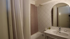 Une salle de bain avec une baignoire, un lavabo et un miroir.