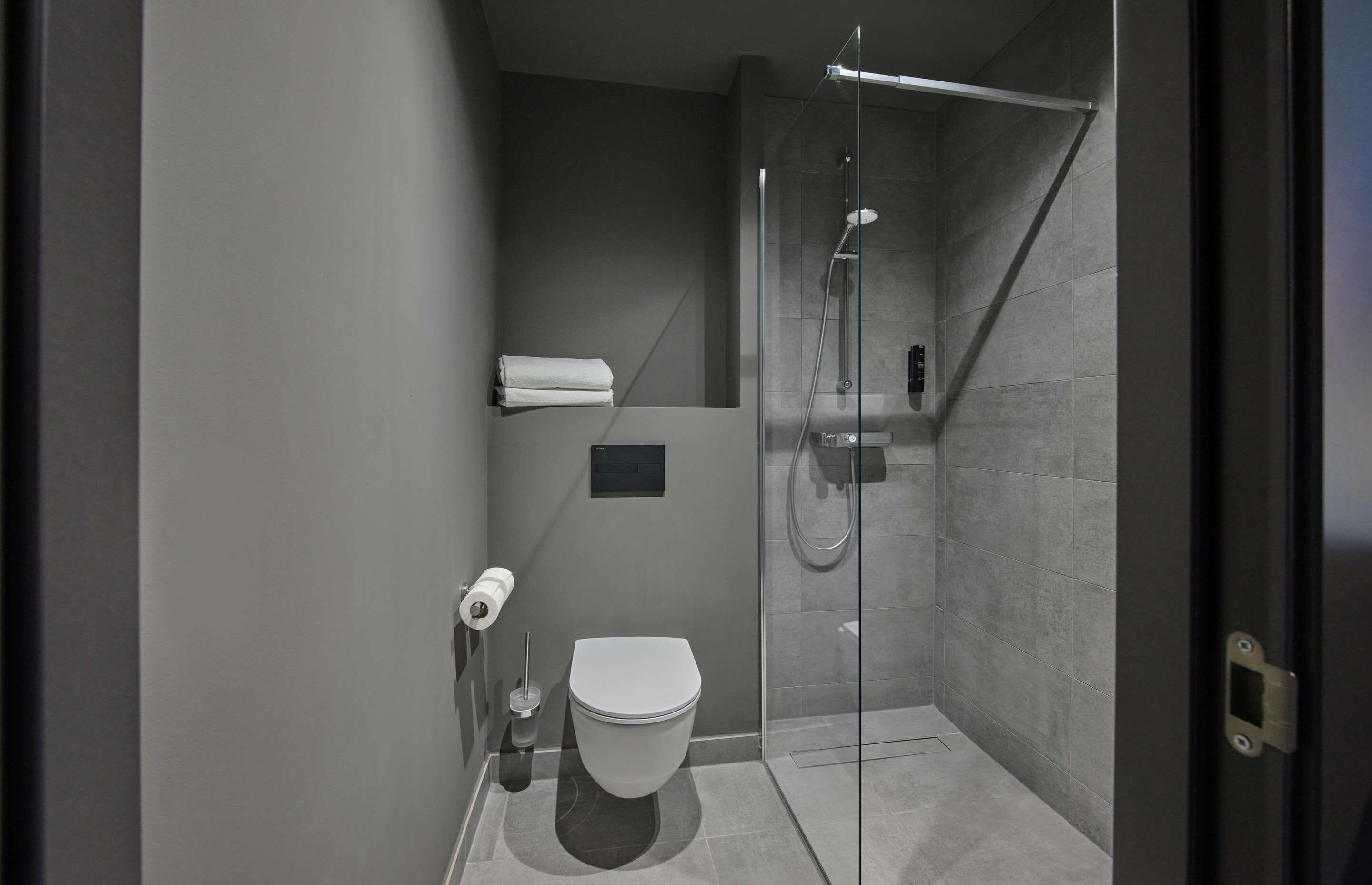 Un baño moderno con ducha de vidrio, inodoro y perchero para toallas.