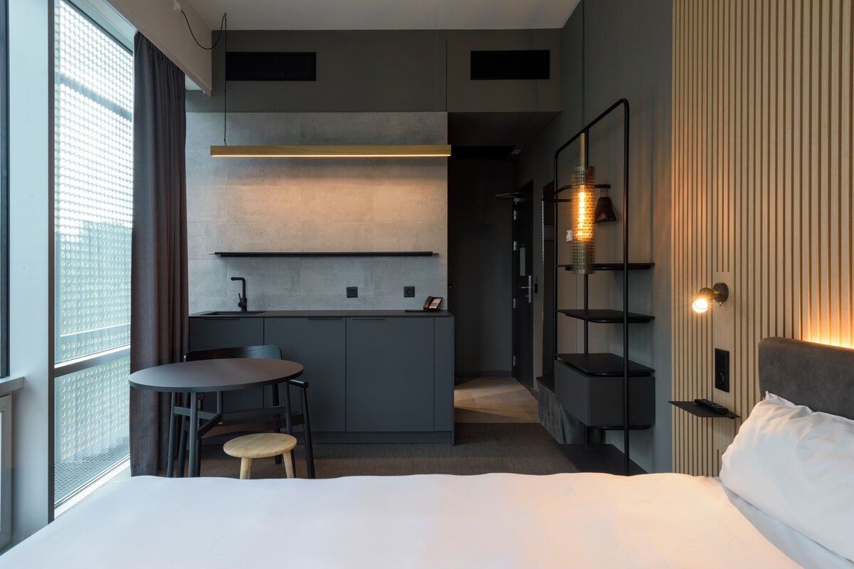 Une chambre d’hôtel moderne équipée d’un lit, d’une petite table à manger et d’une kitchenette.