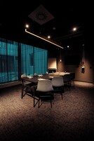 Un salón de conferencias con una gran mesa, sillas, una pizarra y una pantalla de televisión.