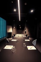 Ein Konferenzraum mit langem Tisch, Stühlen, einer Whiteboard und einer Projektionsfläche.