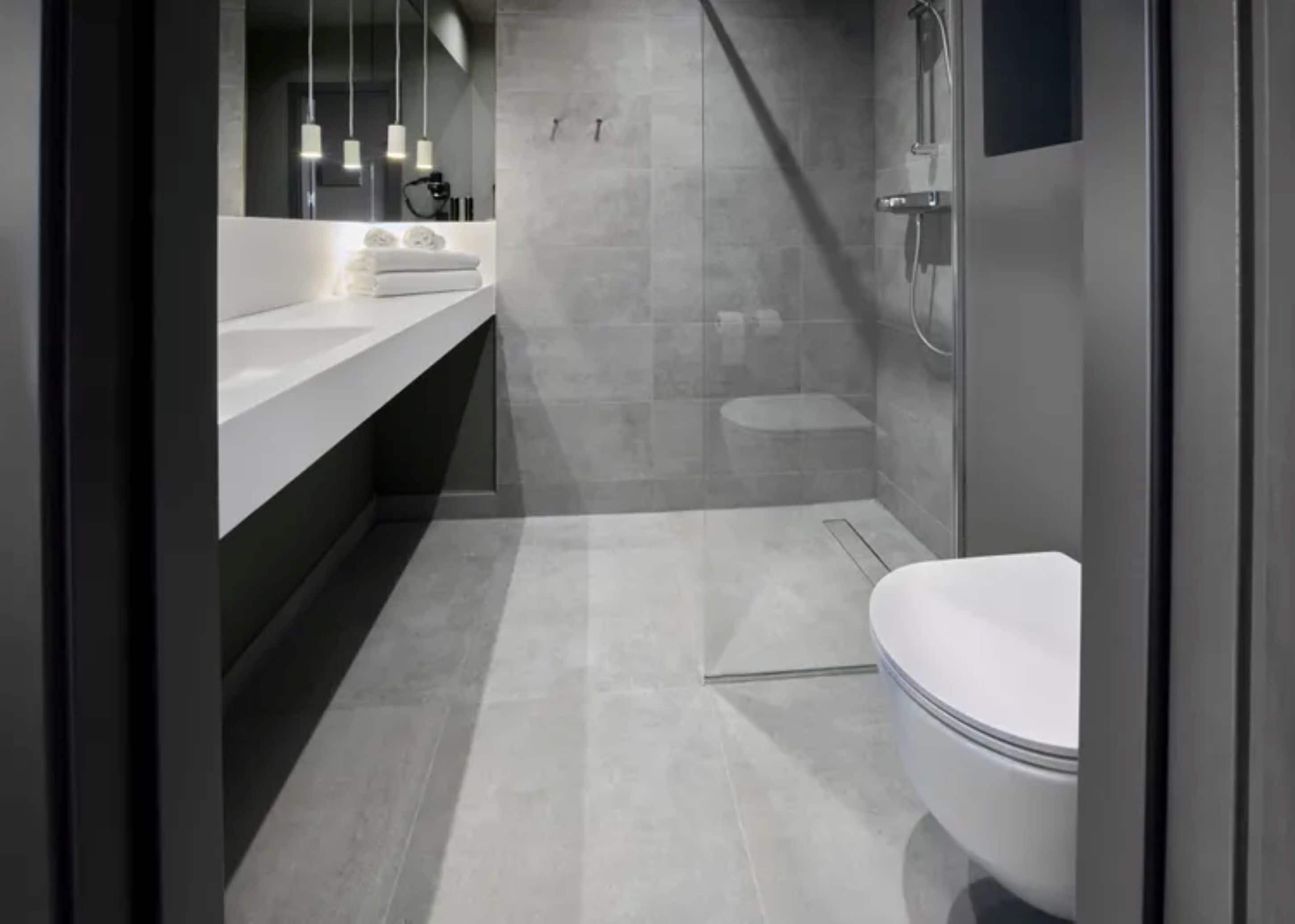 A modern bathroom with a white toilet, a sink with a mirror, and a shower area.