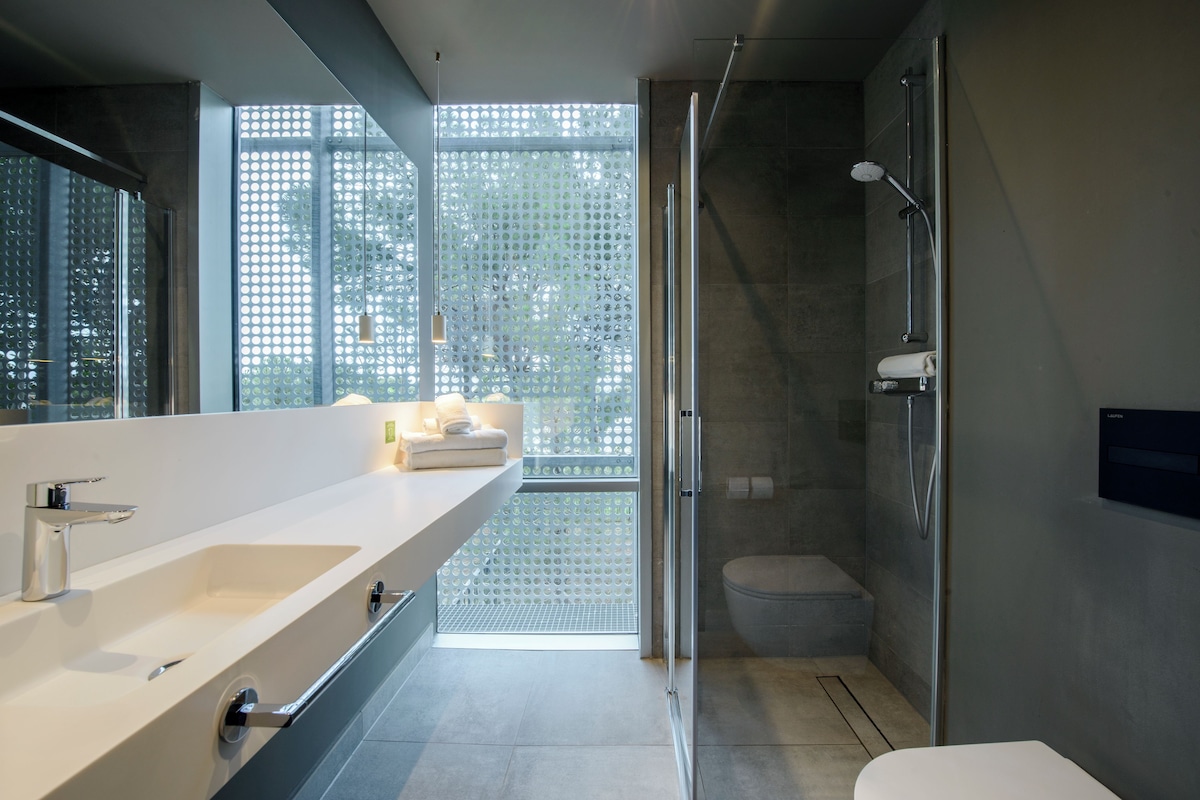 A modern bathroom with a large mirror, a sink, and a shower area.