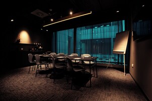 Ein Konferenzraum mit einem großen Tisch, Stühlen, einer Tafel und Blick durch große Fenster.
