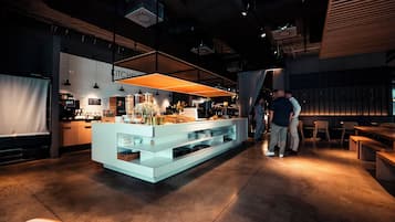 A modern kitchen area with a central island, pendant lighting, and a counter with various items.