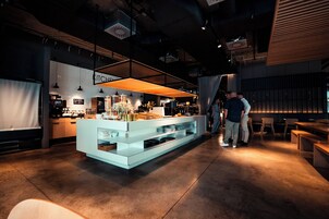 Un área de cocina moderna con una isla central, iluminación colgante y una encimera con varios objetos.