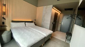 Ein modernes Schlafzimmer mit einem großen Bett, einem Nachttisch, einer Wandleuchte und einer Tür zu einem Schrank.