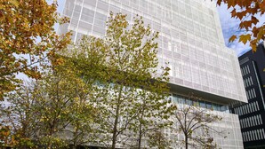 A modern building with a glass facade, surrounded by trees with autumn leaves. - Zleep Hotel Madrid Airport (Madrid)