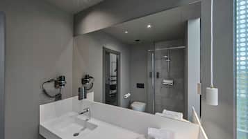A modern bathroom with a large mirror, white sink, and a glass shower enclosure.