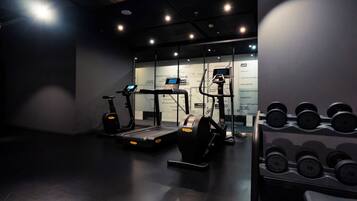 A gym with treadmills, elliptical machines, and a rack of dumbbells.