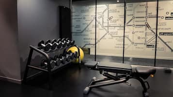 Ein Fitnessraum mit Gewichtsbank, Trainingsbällen und einem Hantelrad.