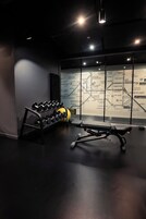 Egy edzőterem, amelyben súlyzóállvány, fitneszlabdák és egy állókerékpár található.