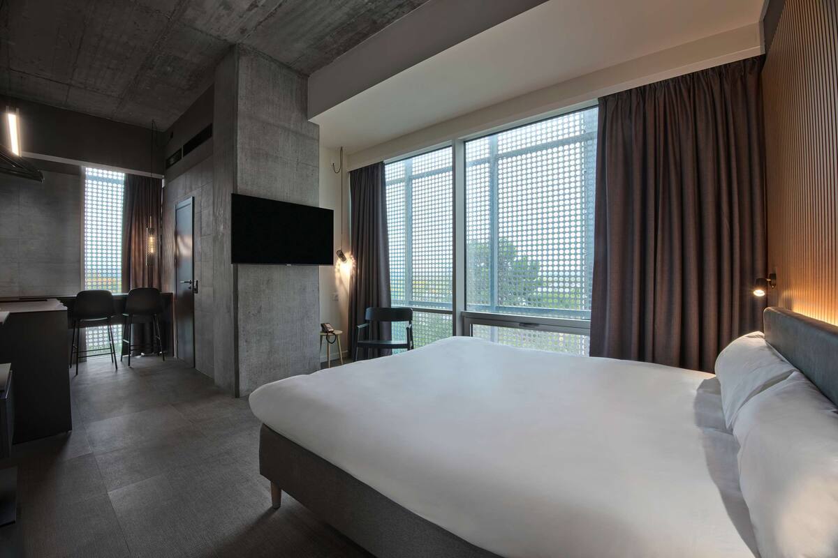 A modern hotel room with a large bed, a desk, and a TV.