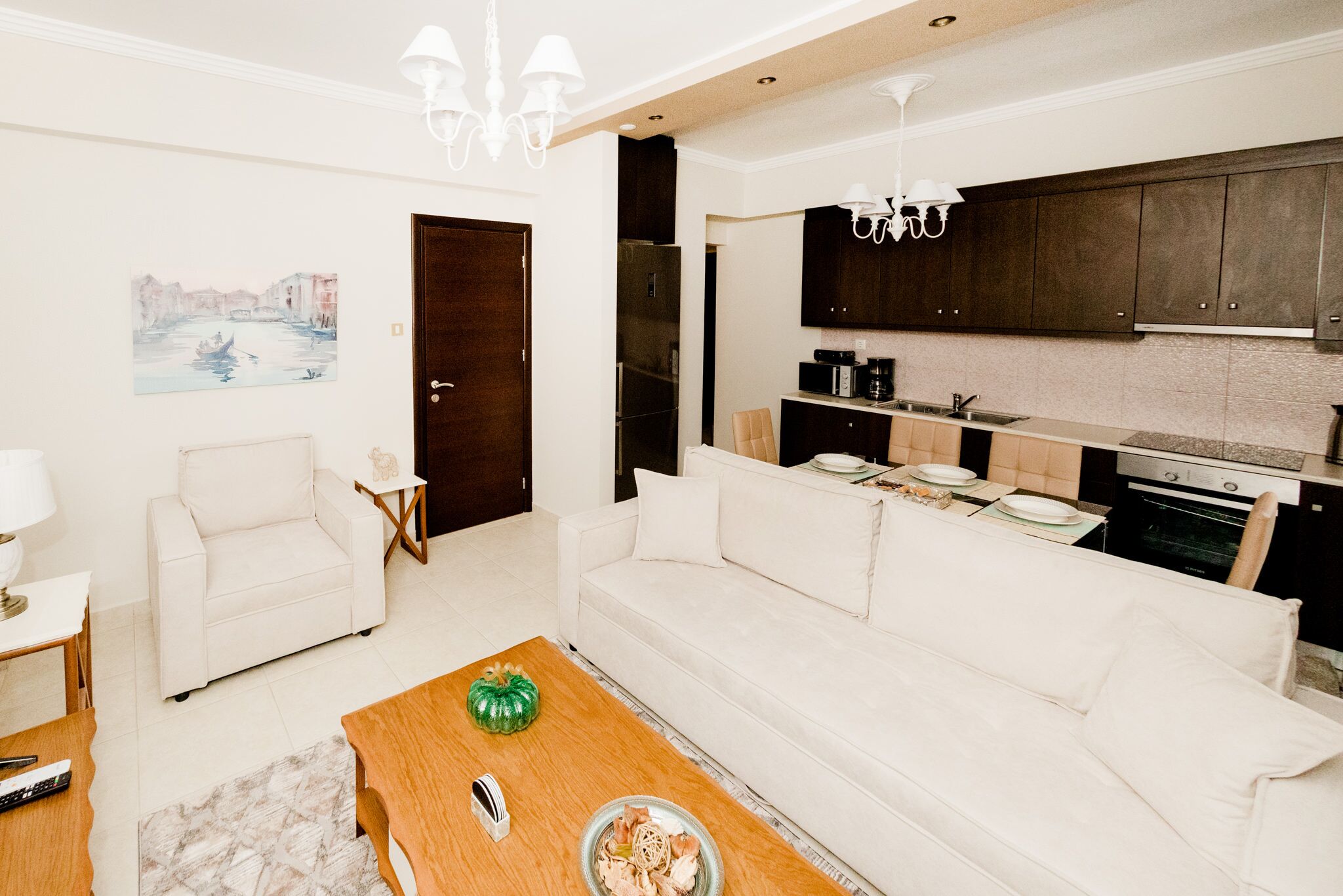 A modern living room with a white sofa, a wooden coffee table, and a painting on the wall.