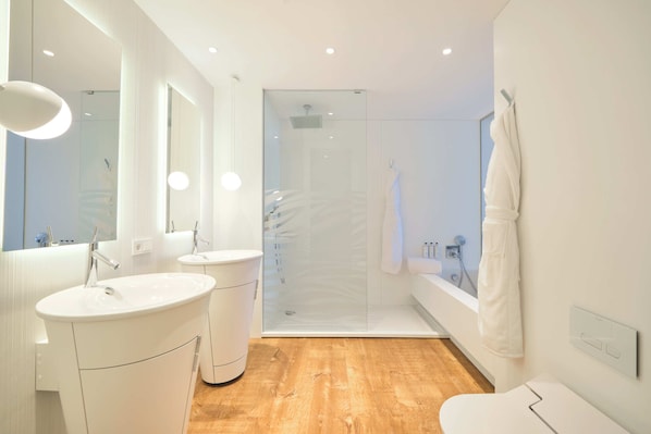 Un baño moderno con dos lavabos, una cabina de ducha con mampara de vidrio y una bañera.