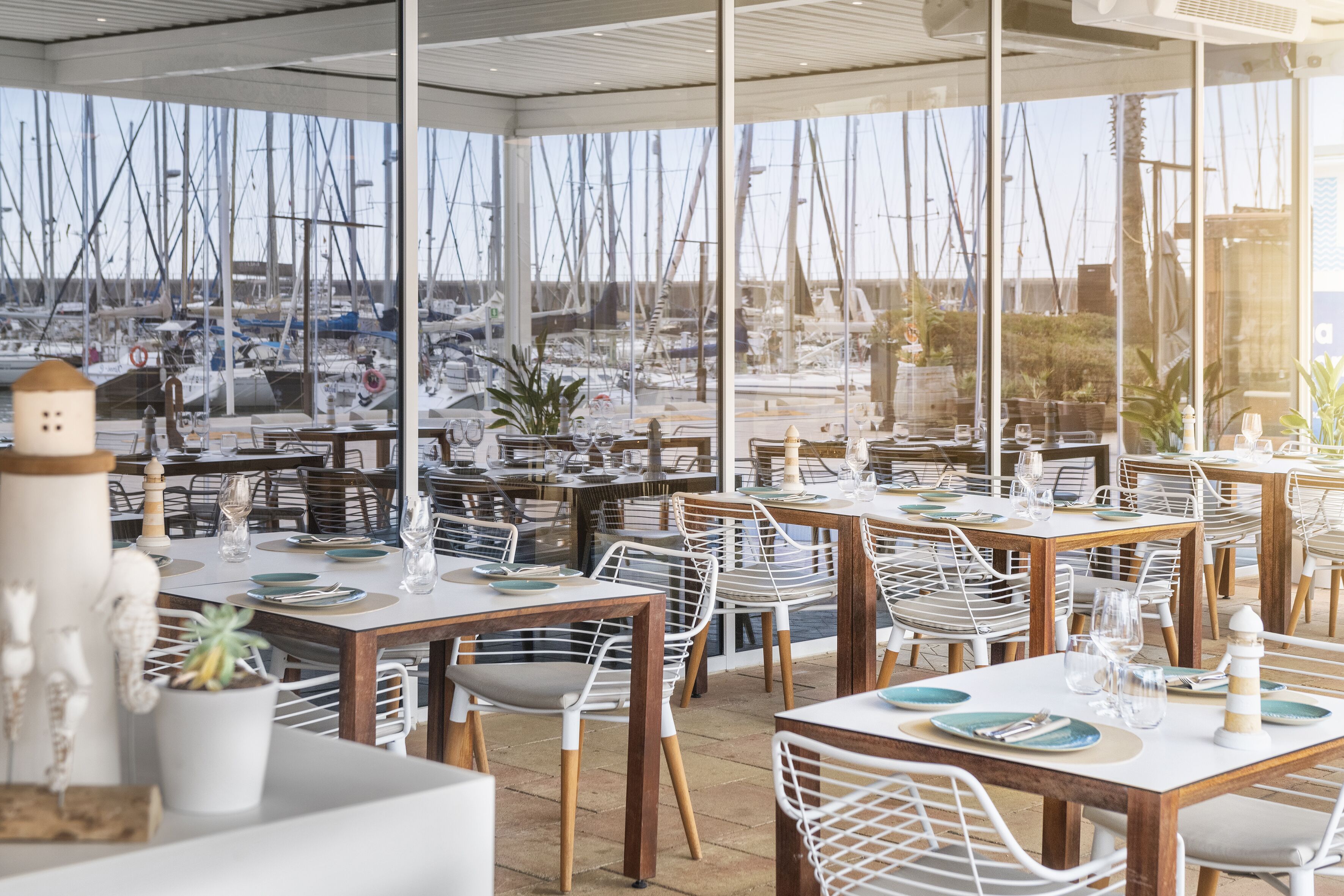 Ein Restaurant mit Außenbereich, weißen Stühlen und gedeckten Tischen.