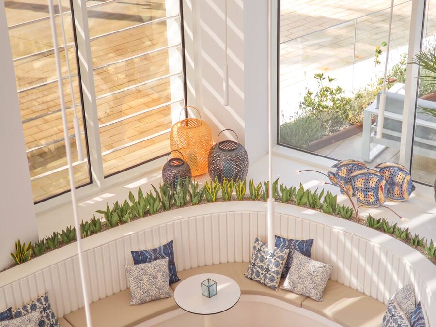 A modern lounge area with a curved seating arrangement, round tables, and a view of the outdoor patio through large windows.