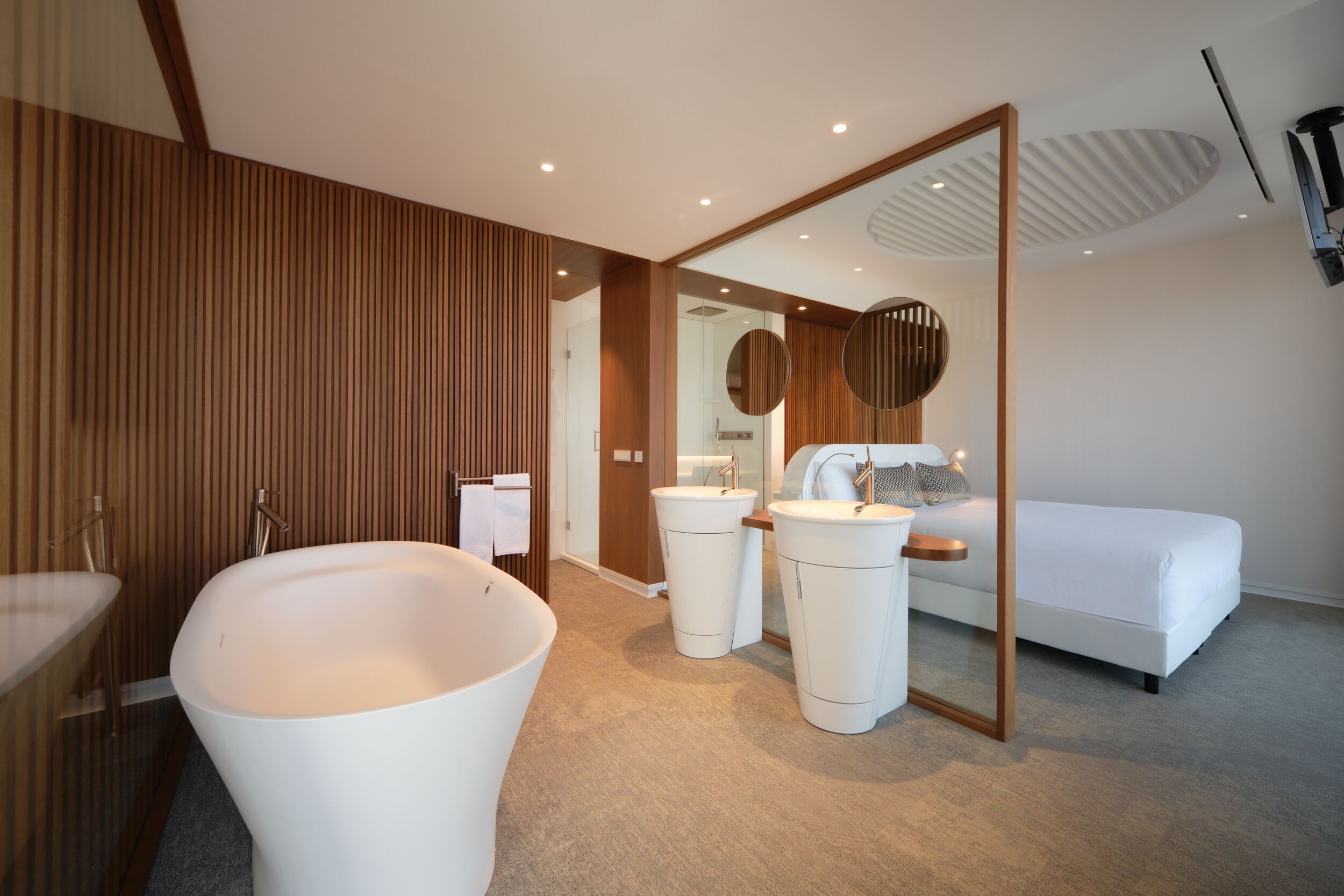 Une salle de bain moderne avec une baignoire sur pieds, deux vasques et un grand miroir.
