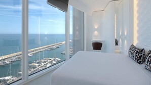 A modern hotel room with a large bed, a view of a marina, and a curved wall design. - Hotel Marina Badalona (Badalona)