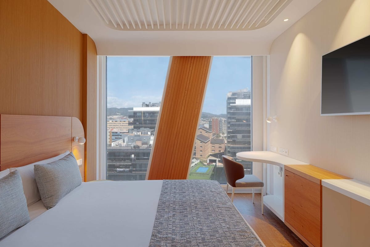 A modern hotel room with a large bed, a desk, and a TV.