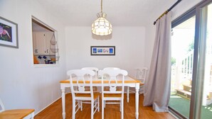 A dining area with a wooden table and white chairs, a hanging light fixture, and a framed picture on the wall. - Bridgepoint II 5D-Bayfront 94th St, Free WiFi, Pool, W/D, AC (Ocean City)