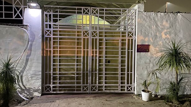 A gated entrance with a metal gate, a concrete wall, and a small potted plant. - Milestone Hotel and Resort (New Delhi)