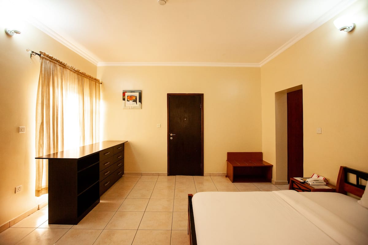 Un dormitorio con cama, cómoda, puerta y una banca.