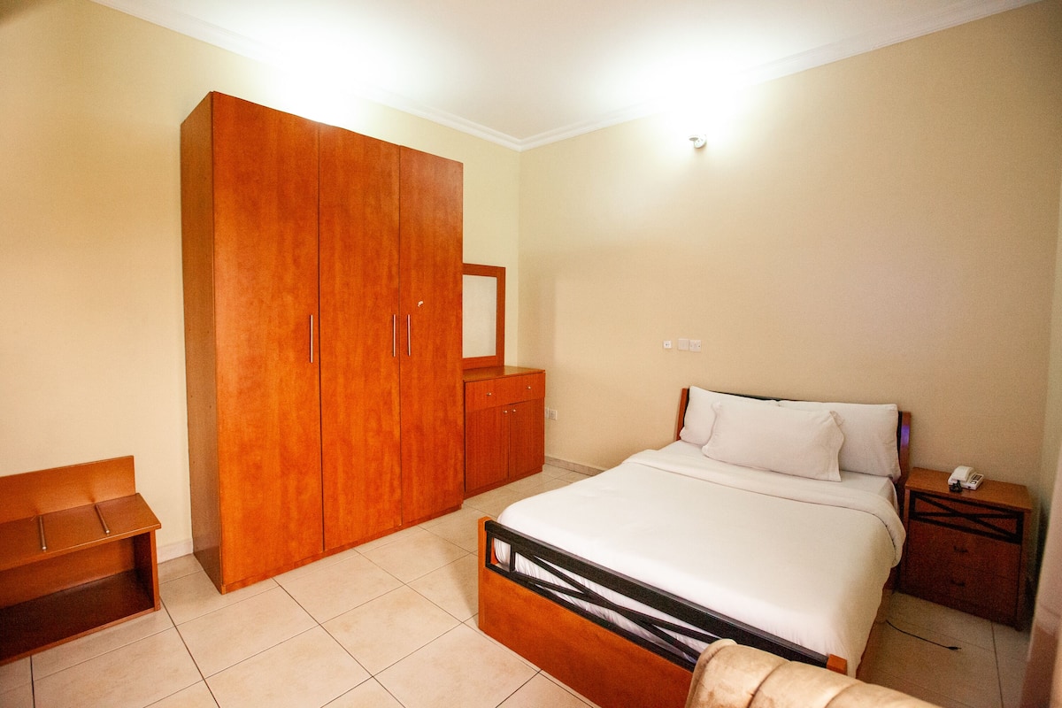 Un dormitorio con cama, armario de madera y mesita de noche.