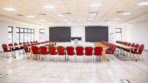 A conference room with a long table and red chairs, large windows, and a blackboard.