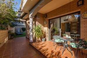 A patio with a table and chairs, potted plants, and a brick wall.