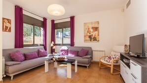 Ein modernes Wohnzimmer mit Sofa, Couchtisch, Fernseher und Sessel.