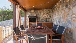 Eine Terrasse im Freien mit Steinmauer, Holztisch und Stühlen.