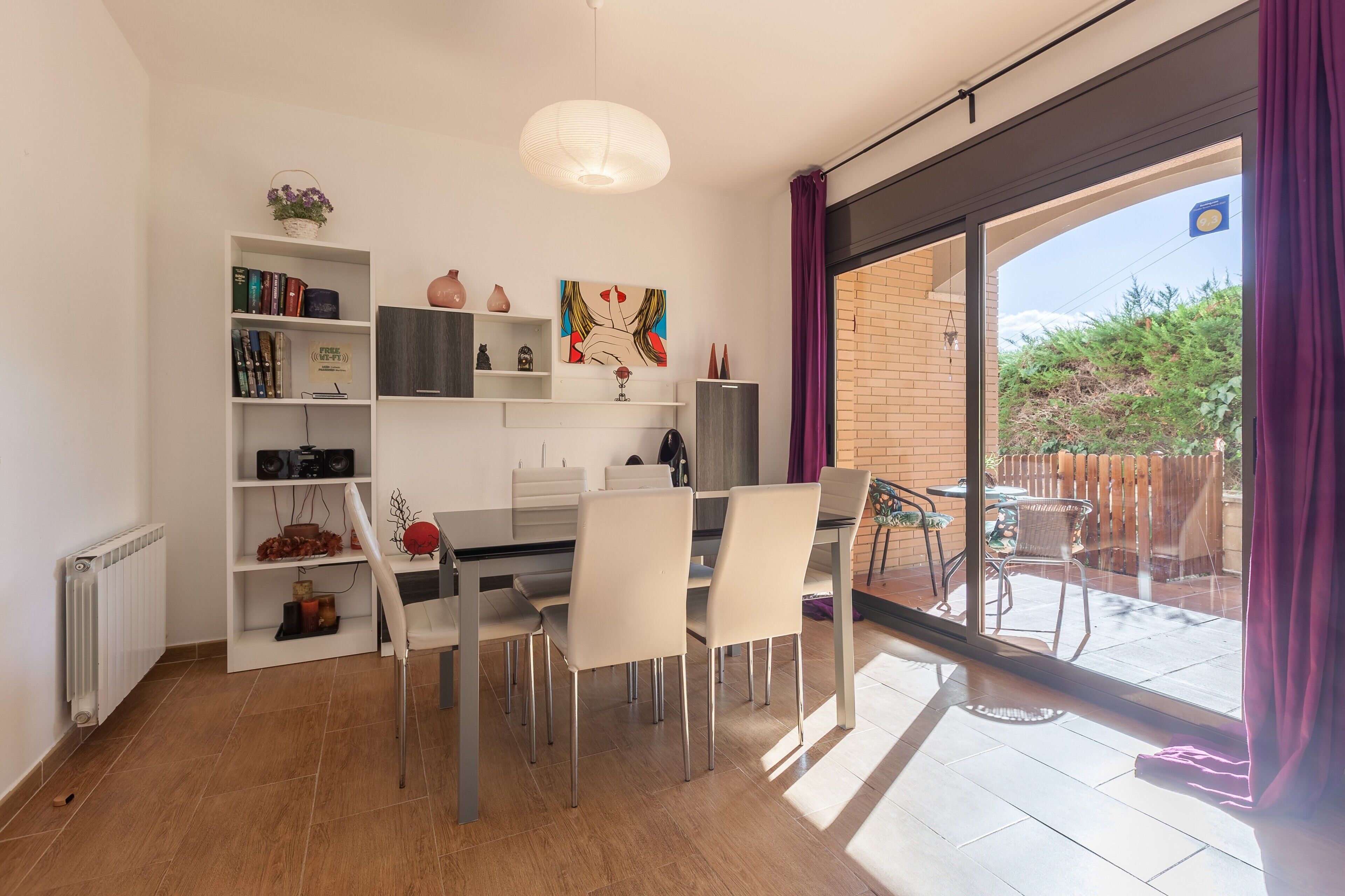 Un comedor moderno con una mesa de vidrio, sillas blancas y una estantería.