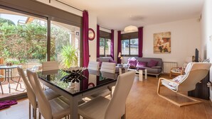 Ein modernes Wohnzimmer mit einem Glastisch, weißen Stühlen, einem grauen Sofa und einem Schaukelstuhl.