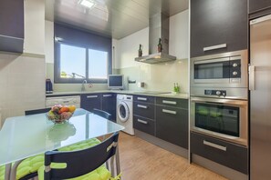 A modern kitchen with a washing machine, a microwave, and an oven. - Vacation Home "Casa Lourdes" with Private Pool, Garden & Wi-Fi (Canyelles)