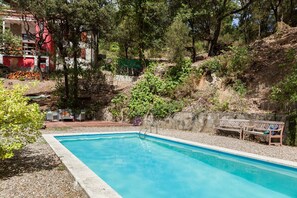 A swimming pool with a stone wall and a wooden bench.