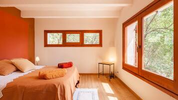 A bedroom with a bed, a nightstand, a lamp, and a window with a view of trees.