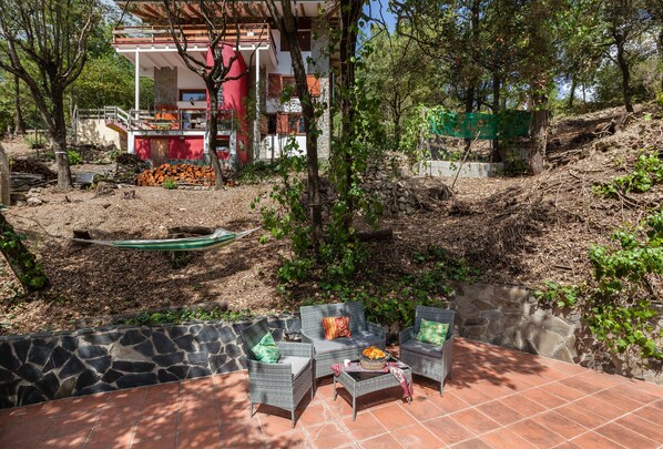 A patio area with wicker furniture and a stone wall.