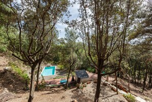 A natural outdoor setting with a pool, seating area, and a small structure.