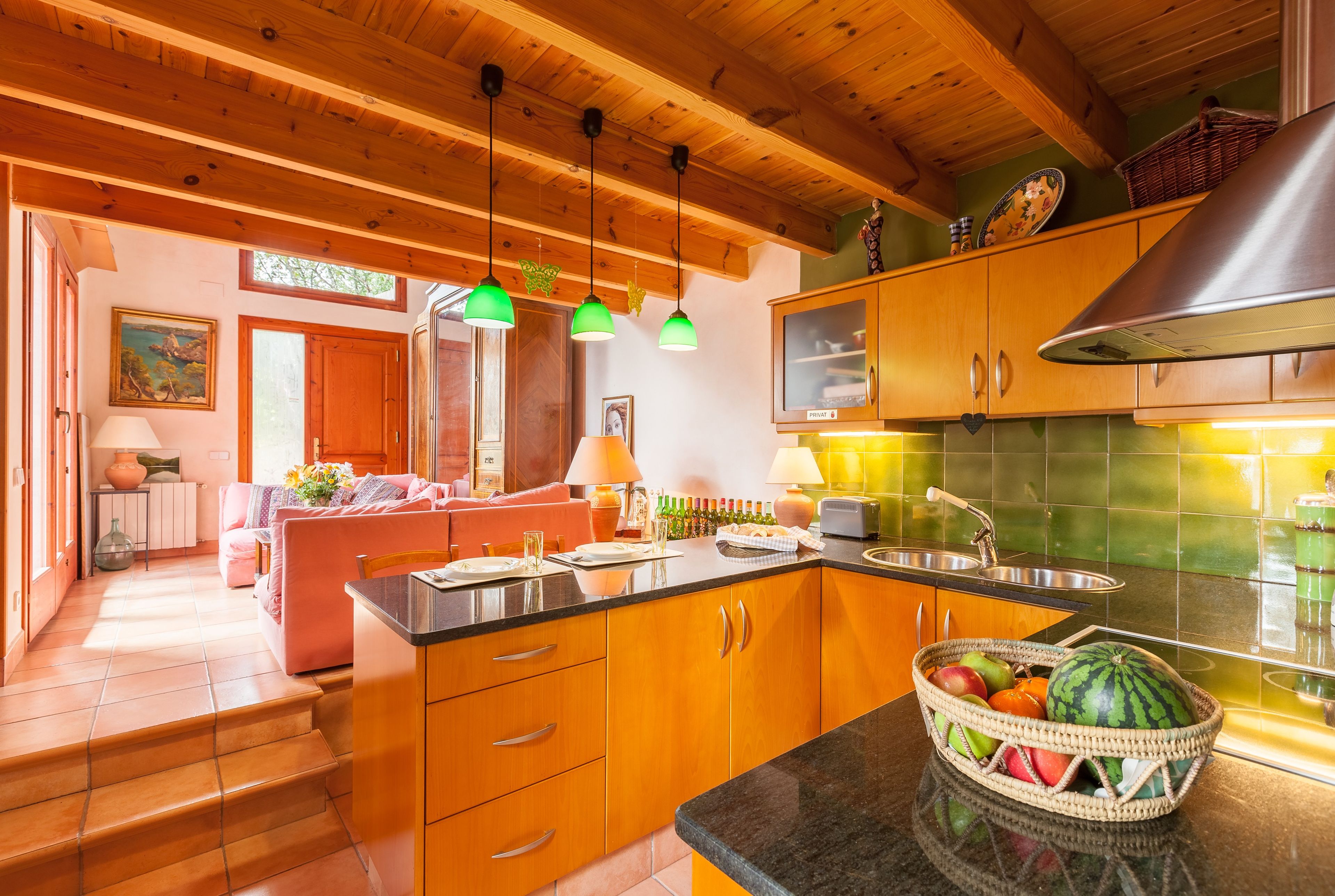 A kitchen with wooden cabinets, a dining area with a sofa, and a view of the outside.