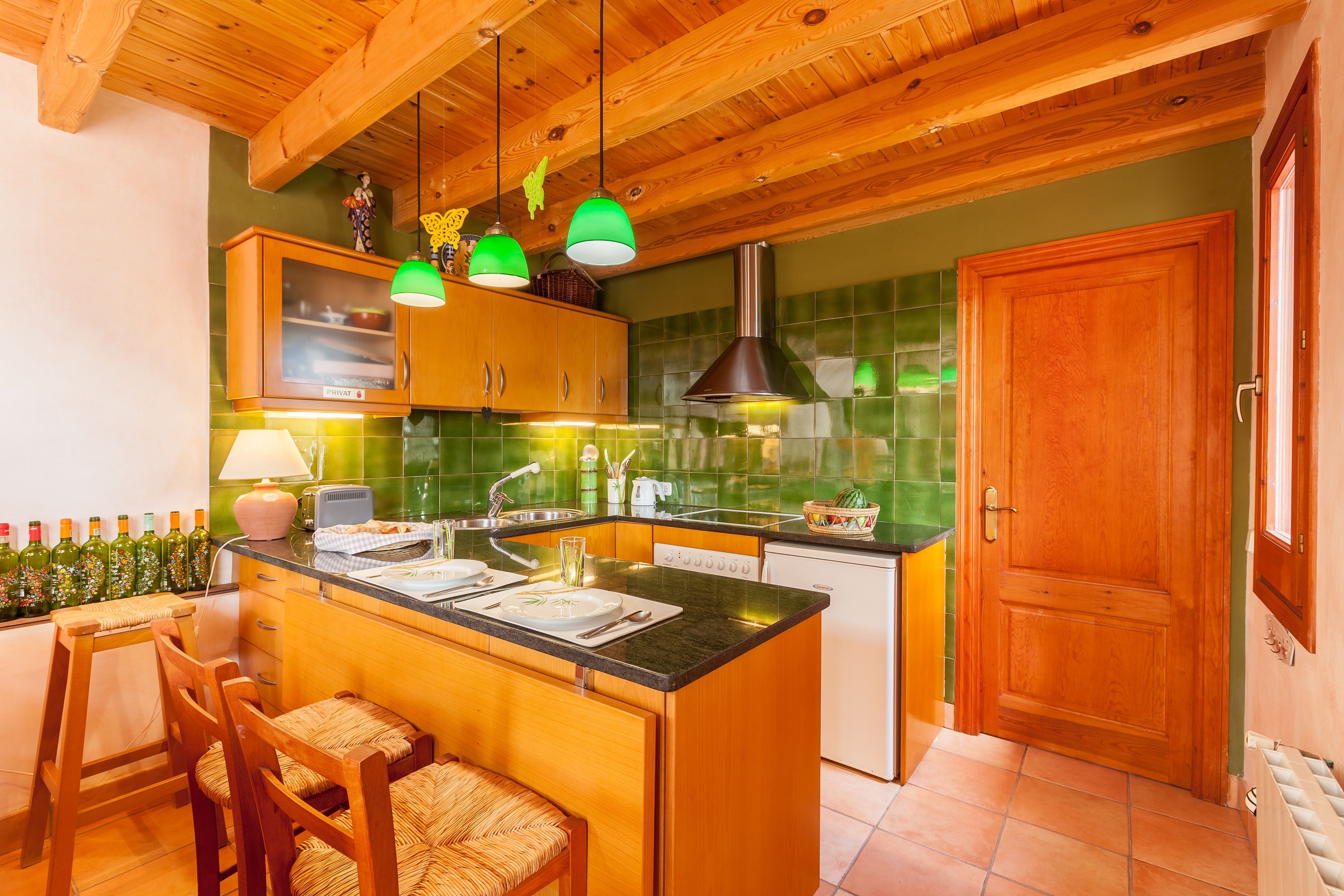 A kitchen with wooden cabinets, a central island, and a green-tiled backsplash.
