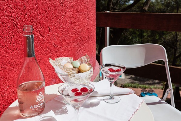 A table with a bottle, a bowl of macarons, and a martini glass with berries.